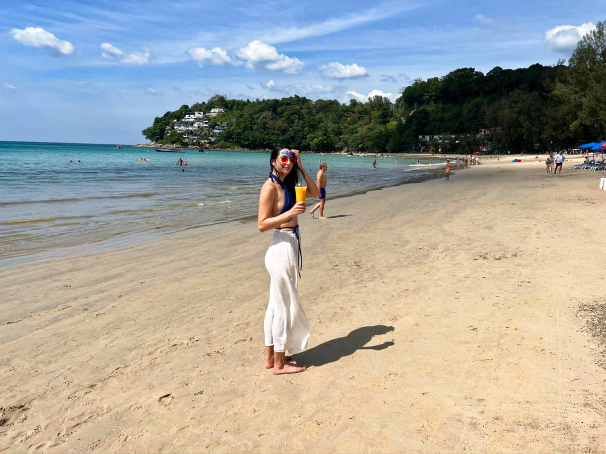 The author's partner, Clara, holding her drink at the shoreline of Kamala