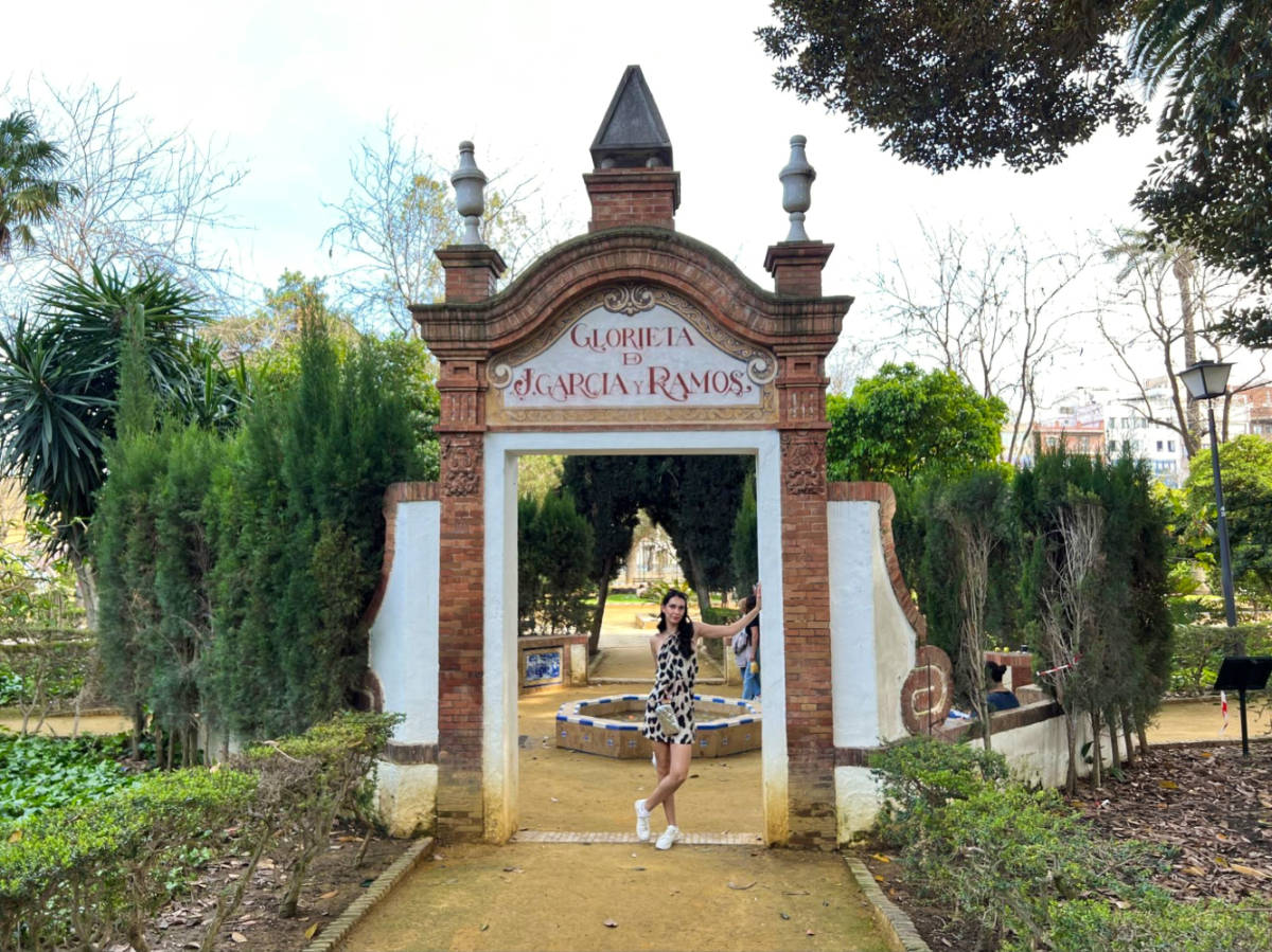 Travel Lemming Writer, Clara, posing for a photo under the arch signage at the Murillo Gardens