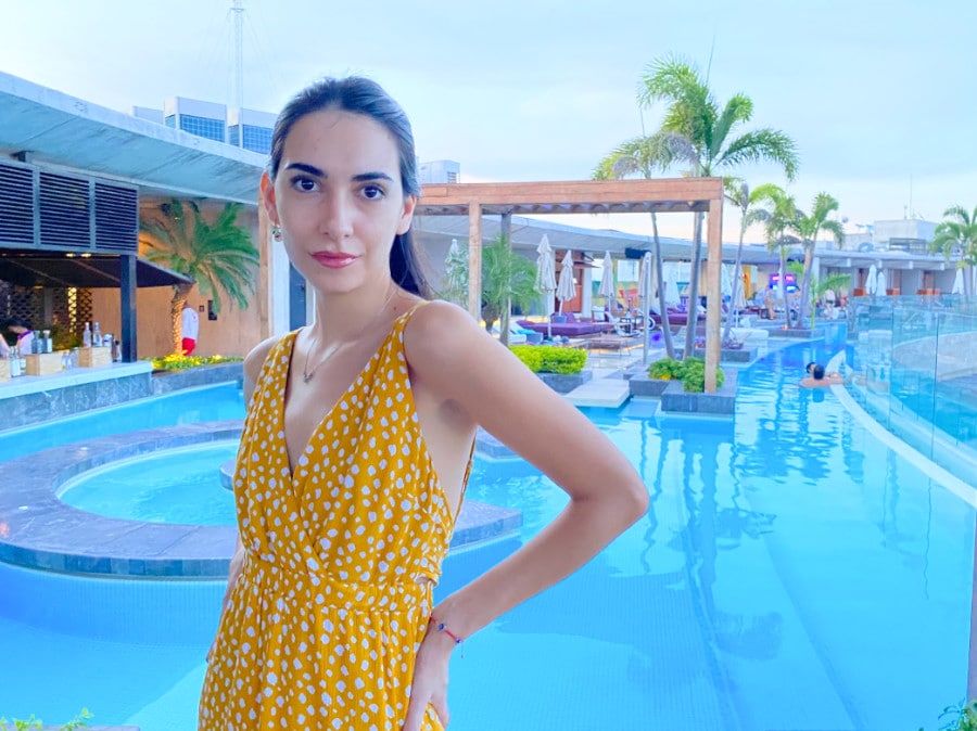 Clara posing for a picture in Thompson Hotel and its pool on her background