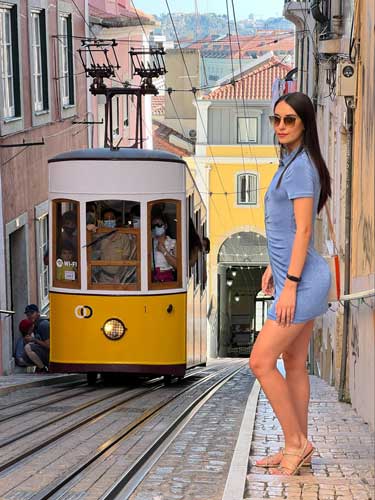 Clara posing for a photo in Bairro Alto with a tram on her background
