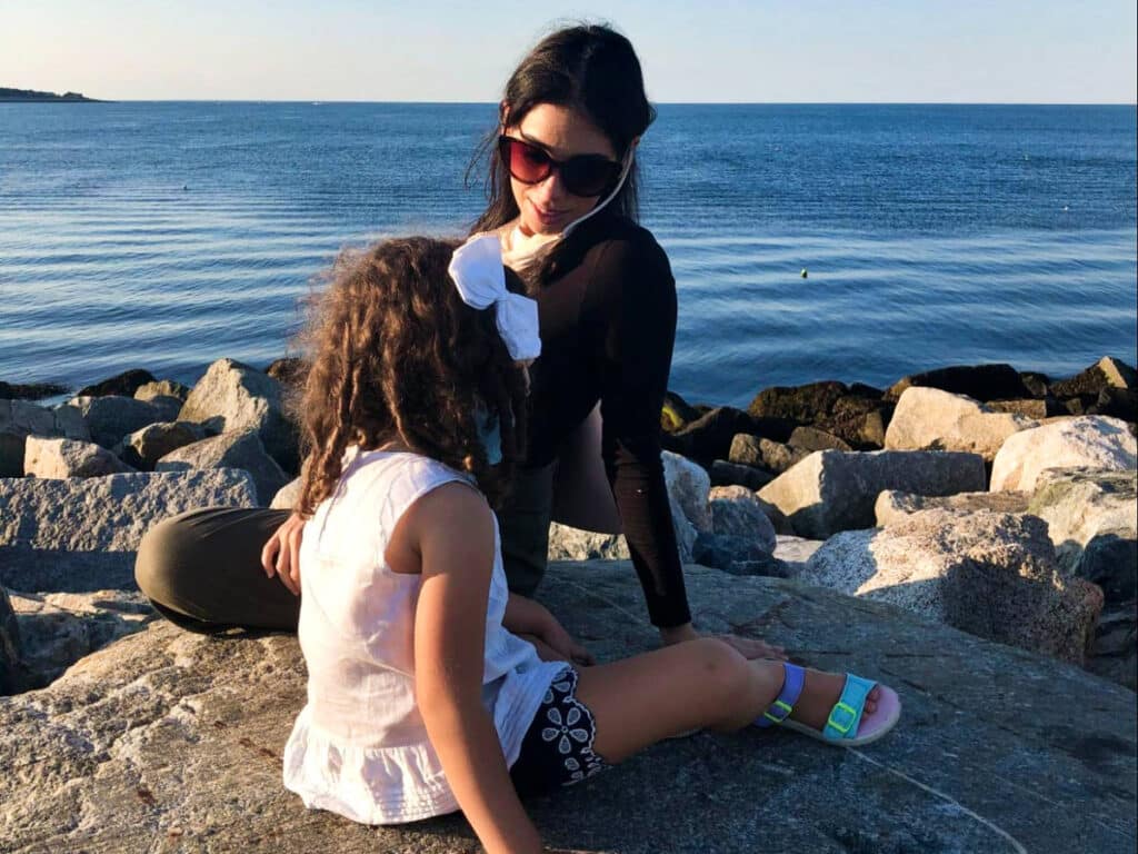 The author Claudicet Peña and her daughter, sitting on a rock at the Bearskin Neck in downtown Rockport