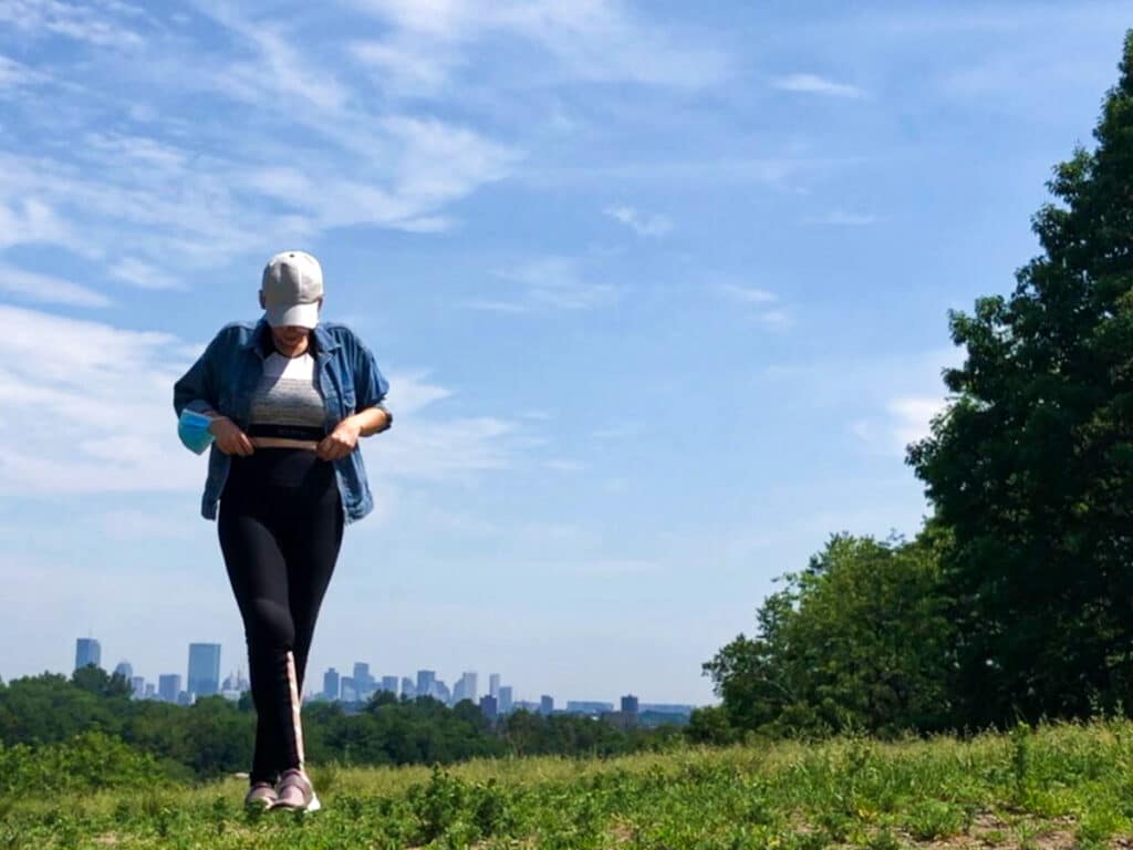 The author Claudicet Peña, posing at the Arnold Arboretum with the Boston skyline in the background