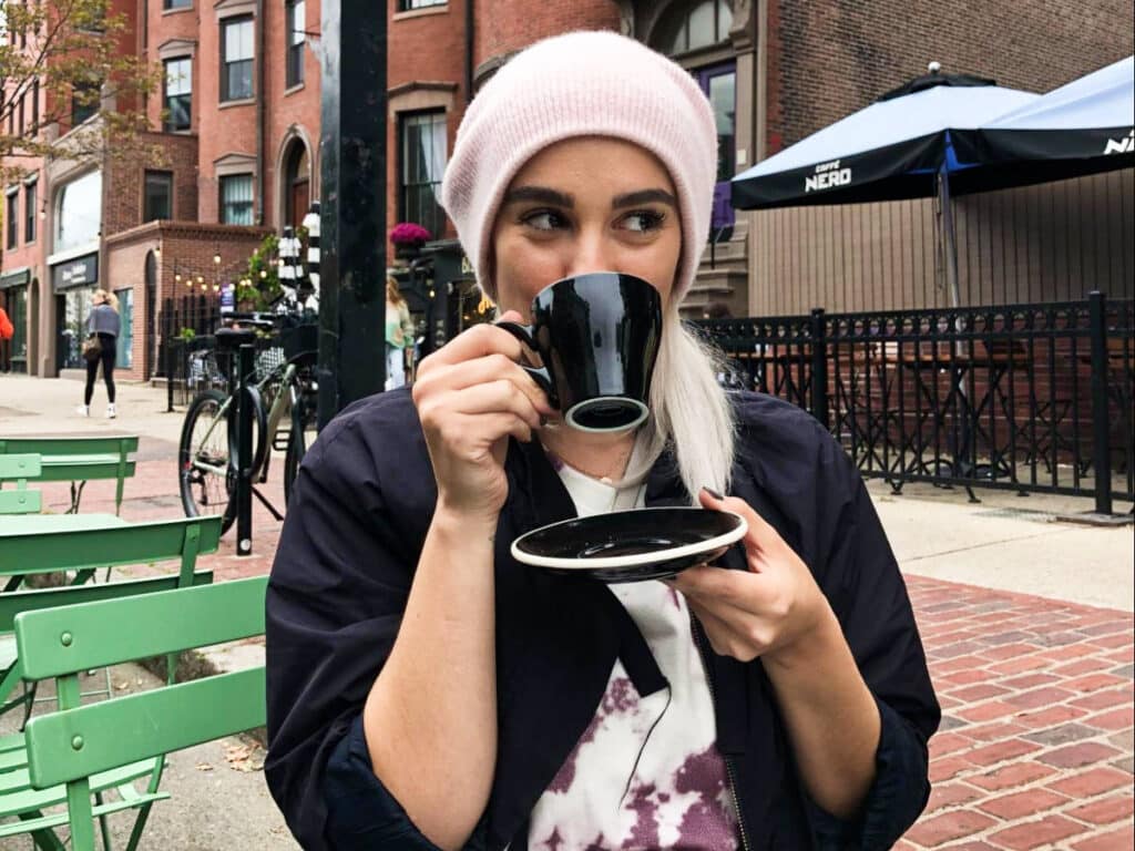The author Claudicet Pena, drinking a coffee at an outdoor patio in South End, Boston
