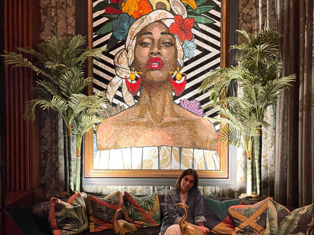 The author Claudicet sitting on the couch with a huge artwork in the background at Maraca Restaurant