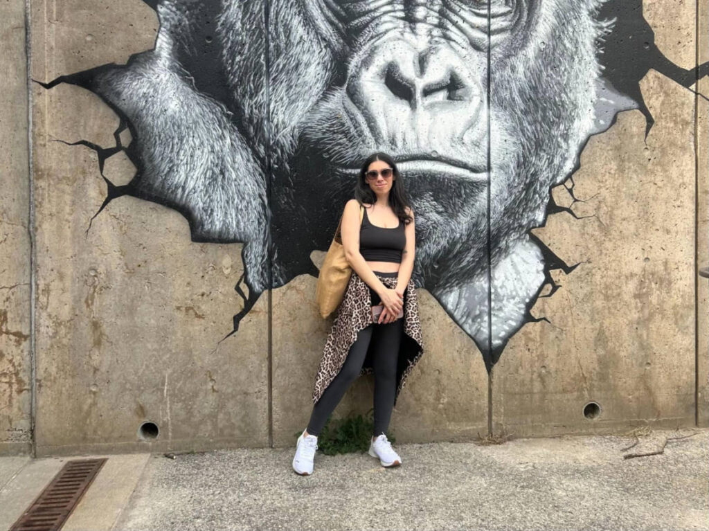 The author Claudicet Pena posing for a photo in front of a mural in Franklin Park Zoo