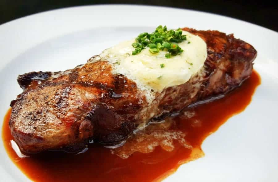 A juicy New York Strip steak, topped with melted cheese served in Cleaver, Las Vegas.