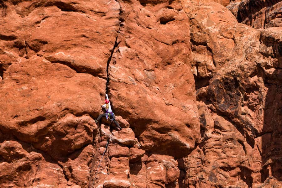 A woman rock climbing on the cliffs of Arches National Park