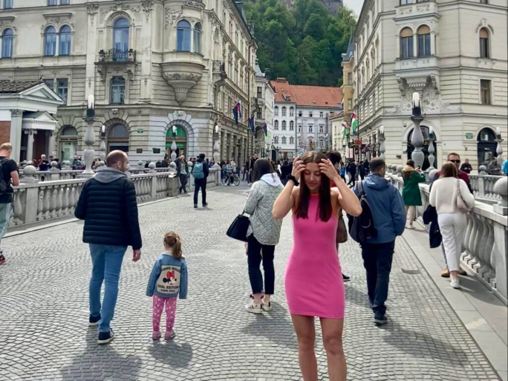 Author Brooke in a pink dress strolling along the cobblestone streets of Ljubljana