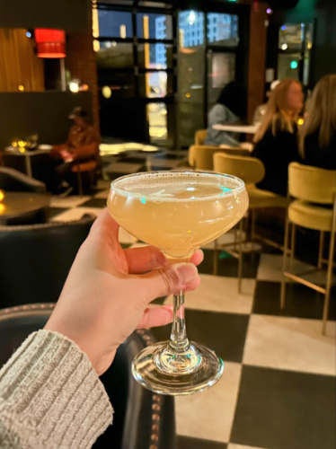 A hand holding a glass of cocktail from The Goldfinch