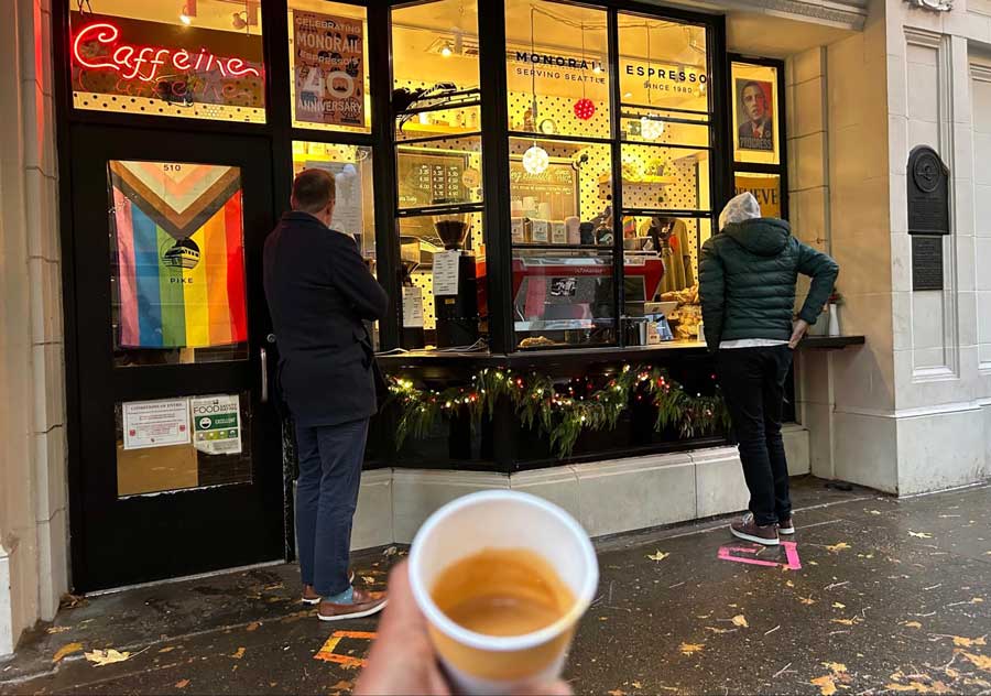 The author holding a cup of coffee outside a coffee shop in Seattle