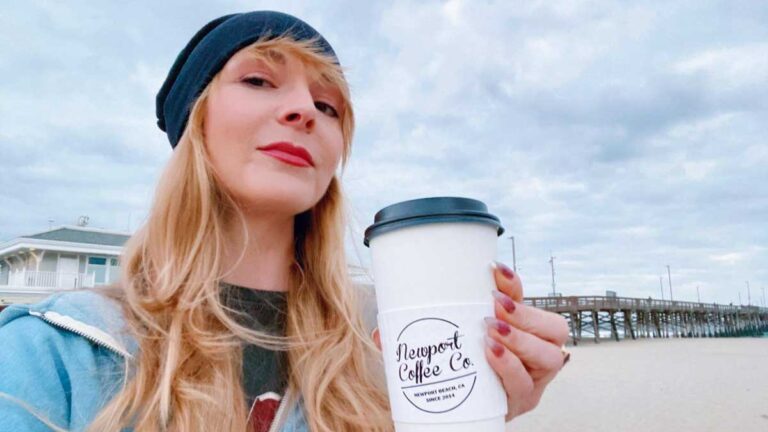The author Jericha Griffin smiling for a selfie while holding her cup of coffee from Newport Coffee Company