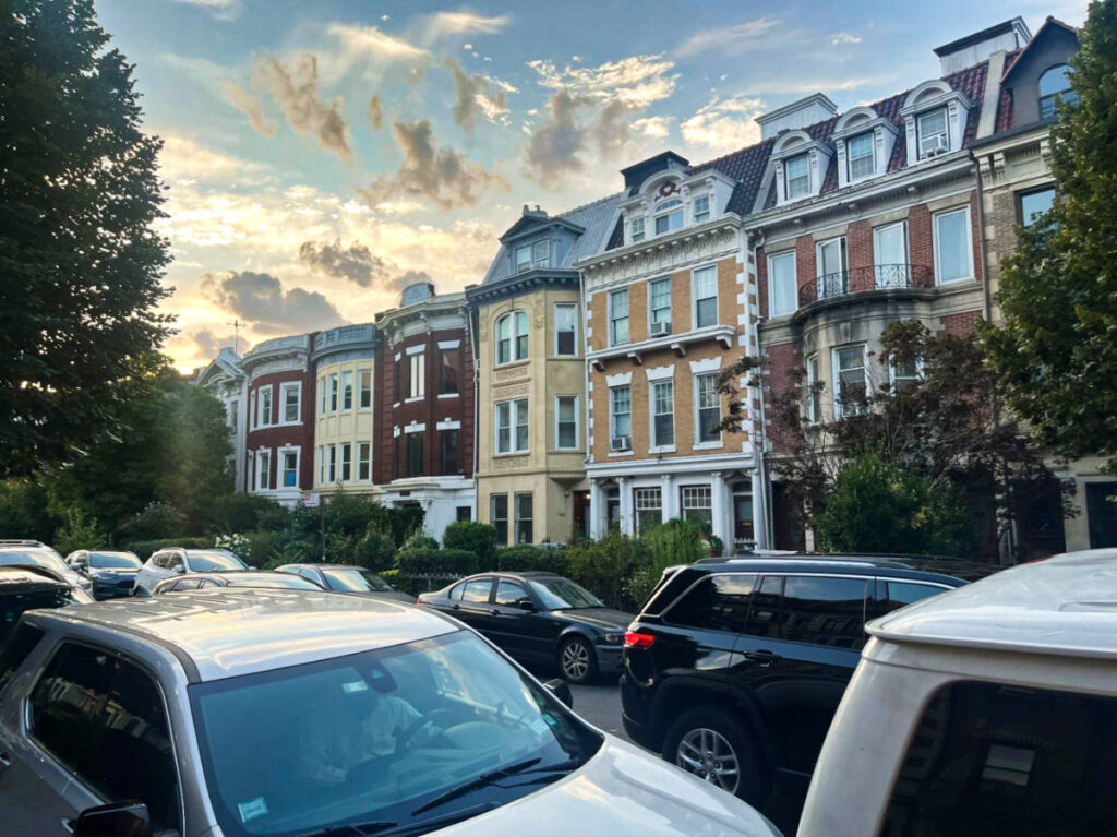 View of the colorful brownstones seen from the road full of cars