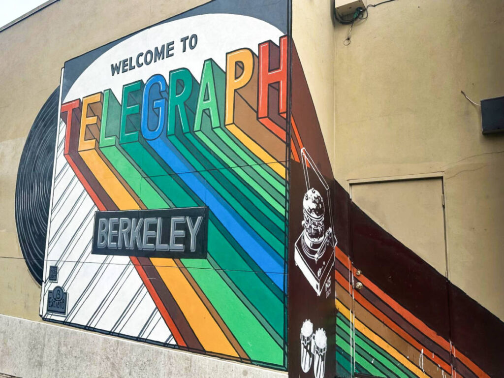A colorful mural of a record player with the welcome signage on Telegraph Avenue