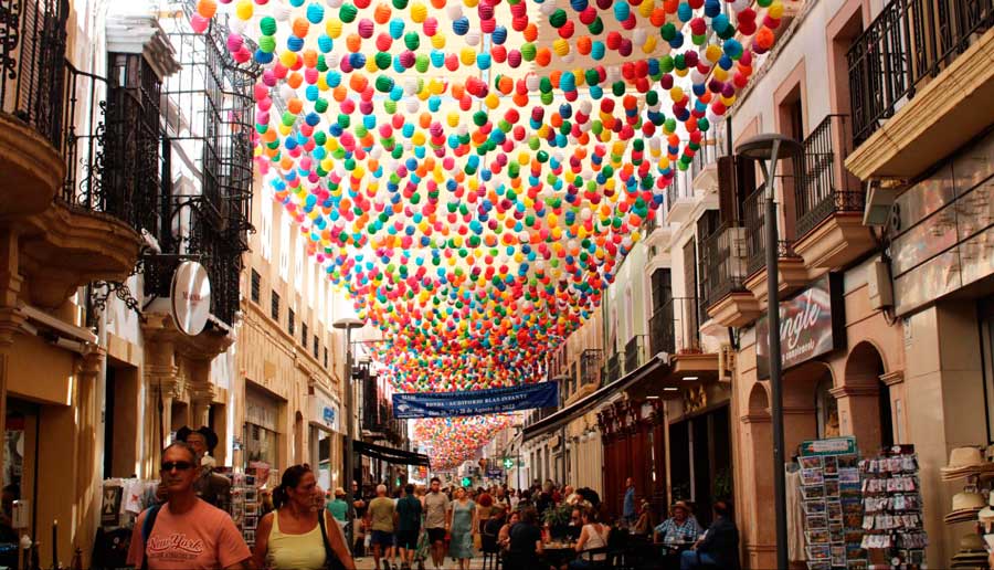 View of a colorful decoration on a street in Spain with tourists walking by