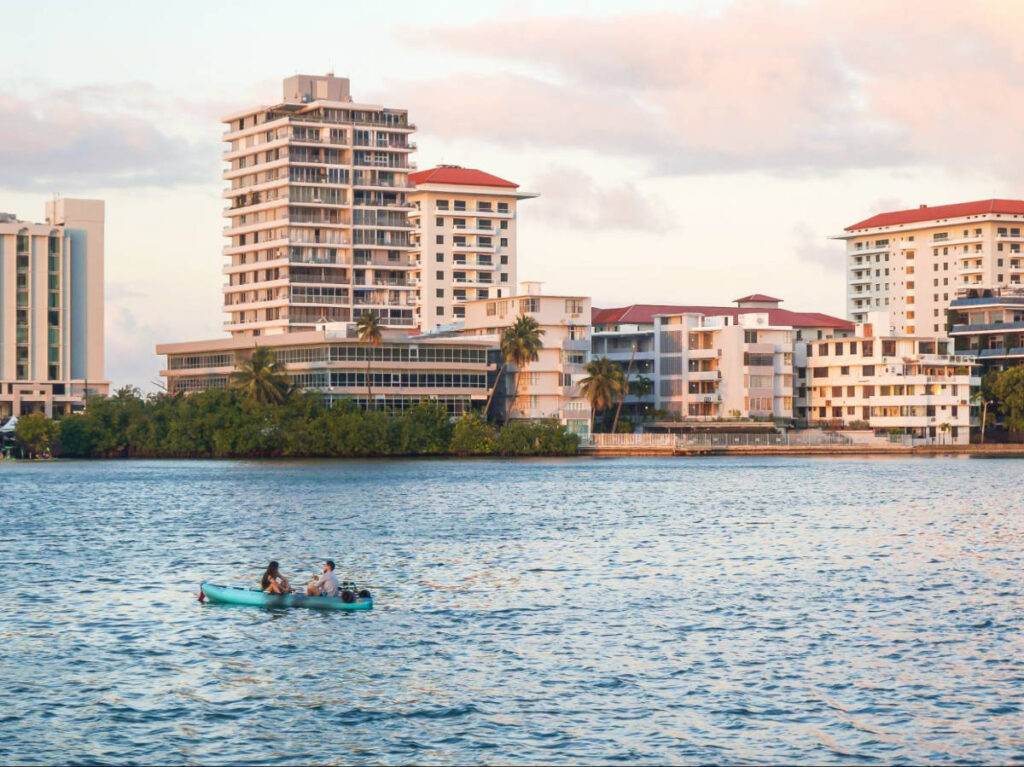 A couple kayaking on the Condado Lagoon with skyline views at sunset
