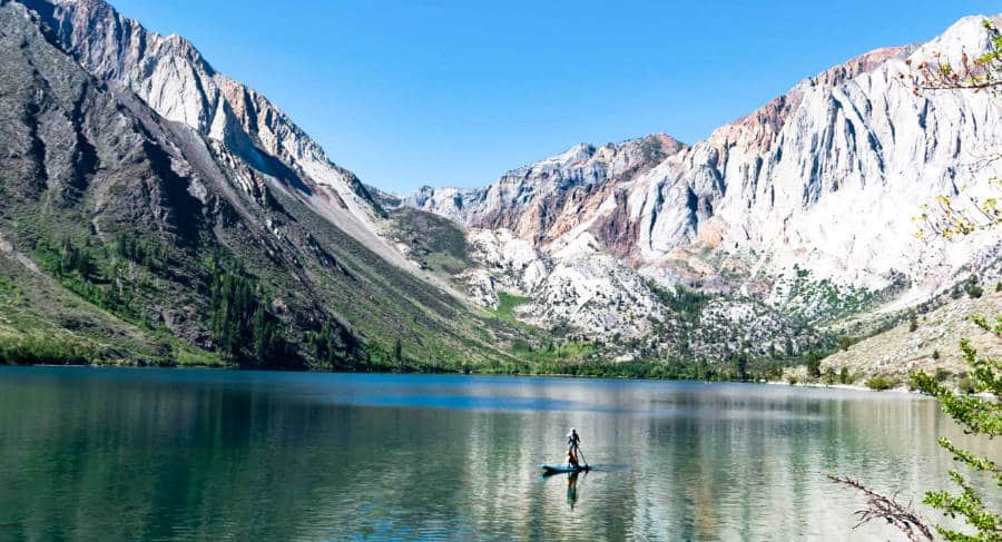 A man and his dog on a standup paddle at the picturesque view of Convict Lake.