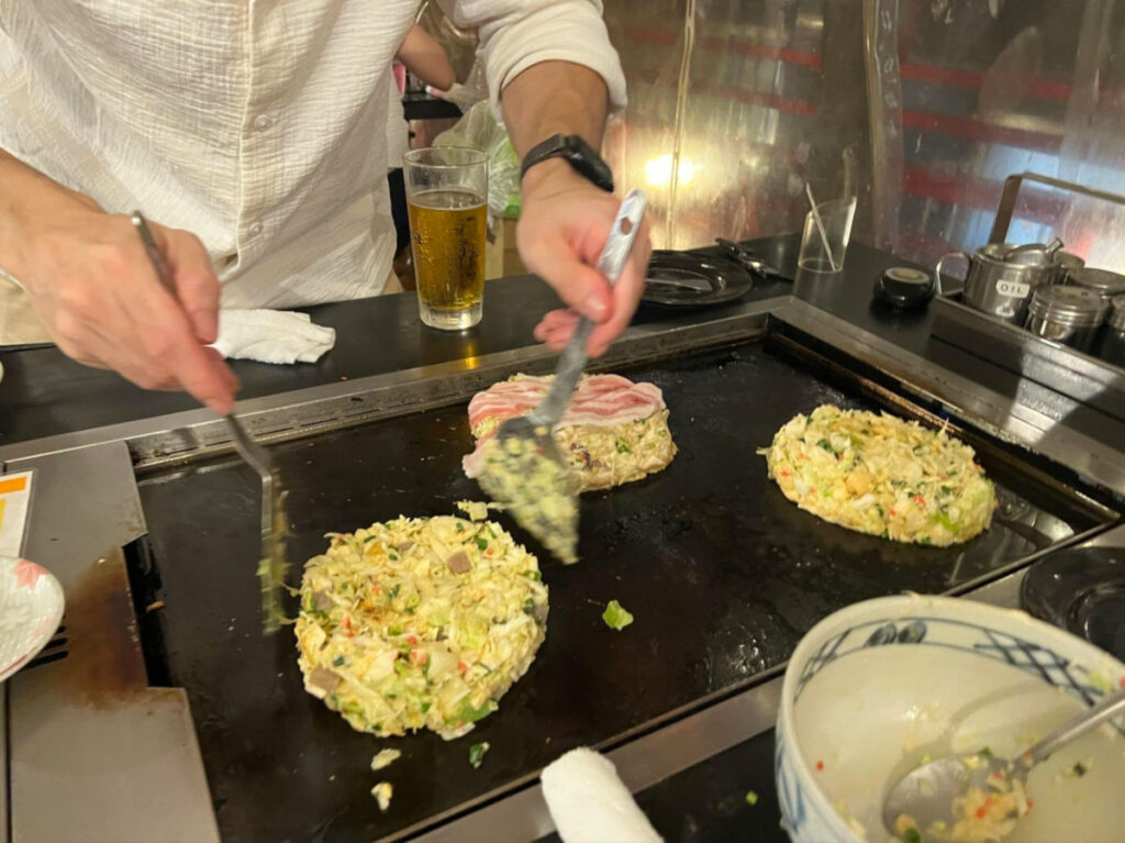 A man cooking okonomiyaki at Sakura-tei