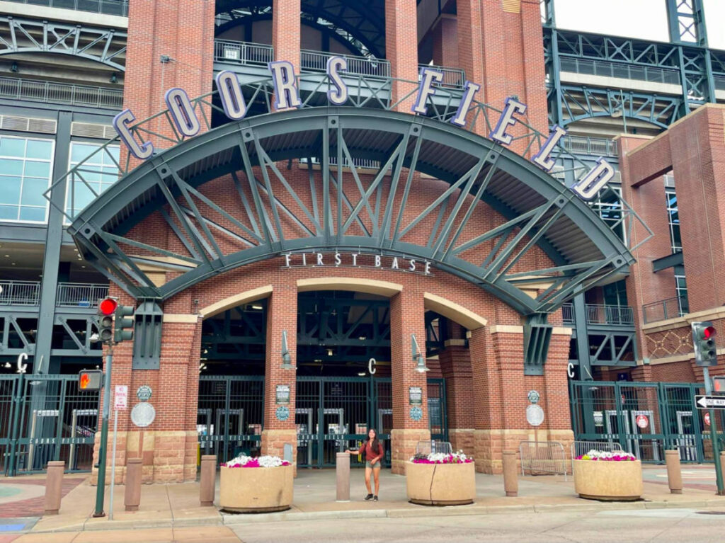 Travel Lemming editor Abigail standing at the entrance to Coors Field stadium
