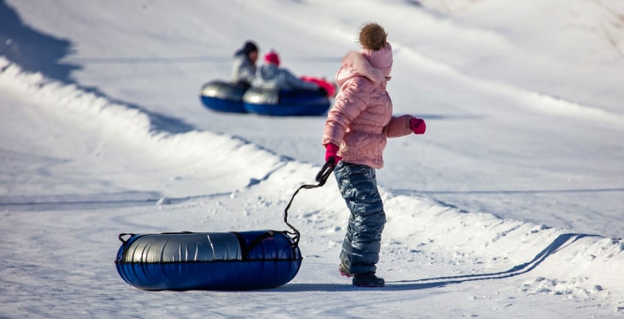 People snow tubing down a slope in winter