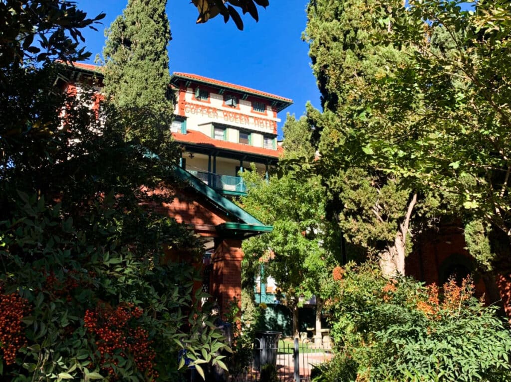 Exterior view of Copper Queen Hotel surrounded by greenery in downtown Bisbee