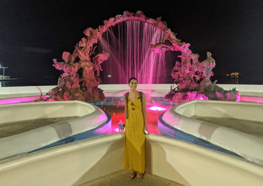 Clara posing for a picture and a water fountain monument on her background