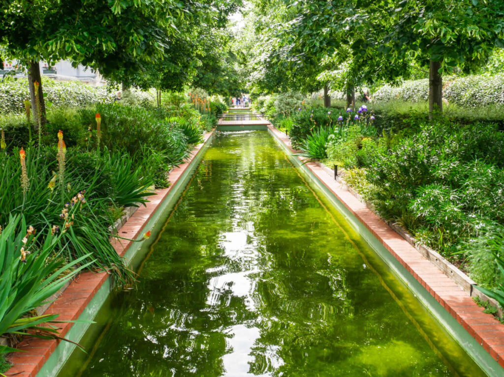 View of the green water canal surrounded by greenery in Coulée Verte René-Dumont