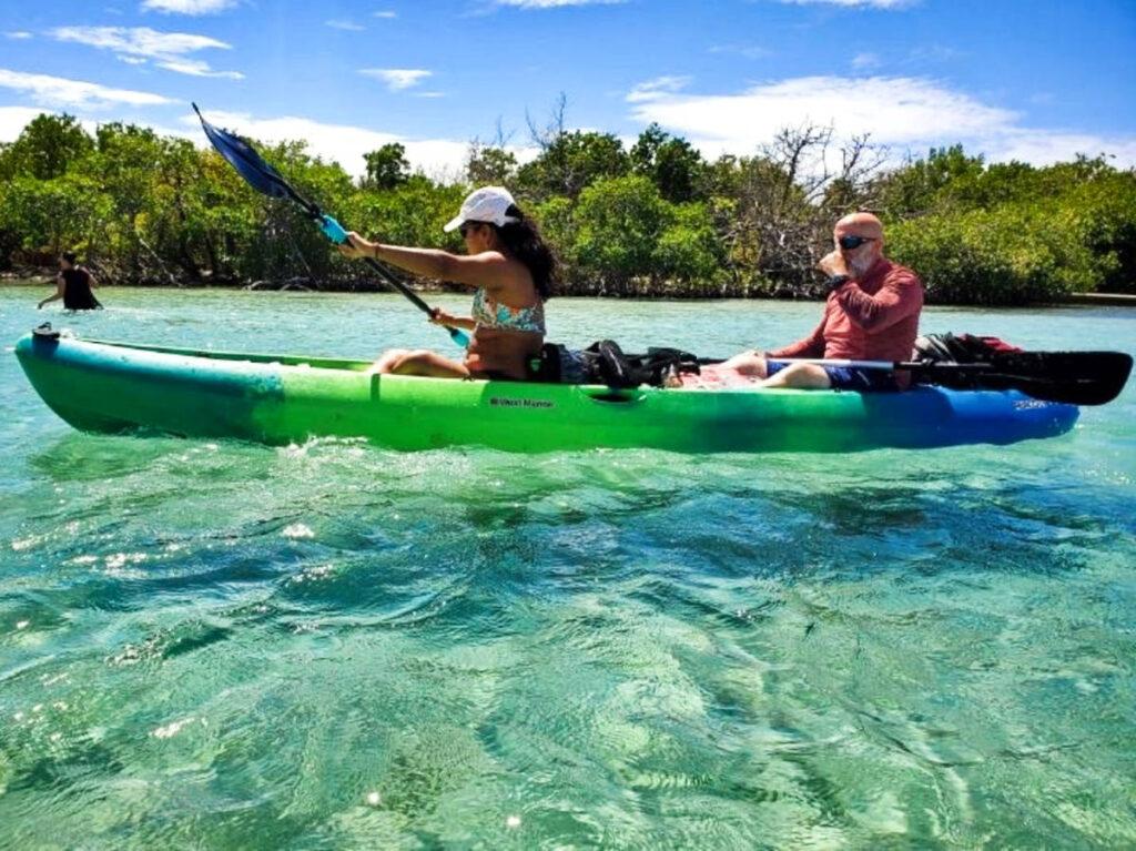 A couple kayaking on the clear water at Gilligan Island