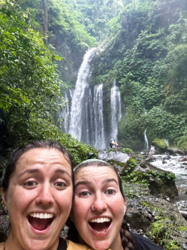 The author Laura McFarland and her partner posing for a photo in front of the Tiu Kelep Waterfall