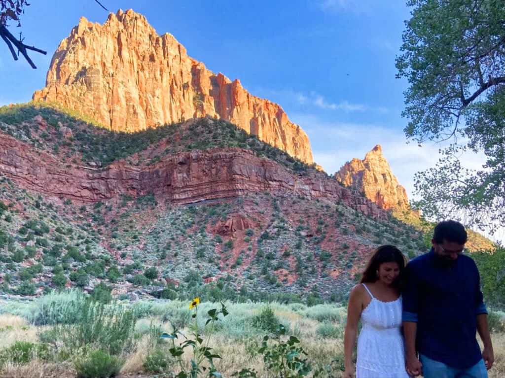 A couple posing for photos with the rock formations in the background in Springdale