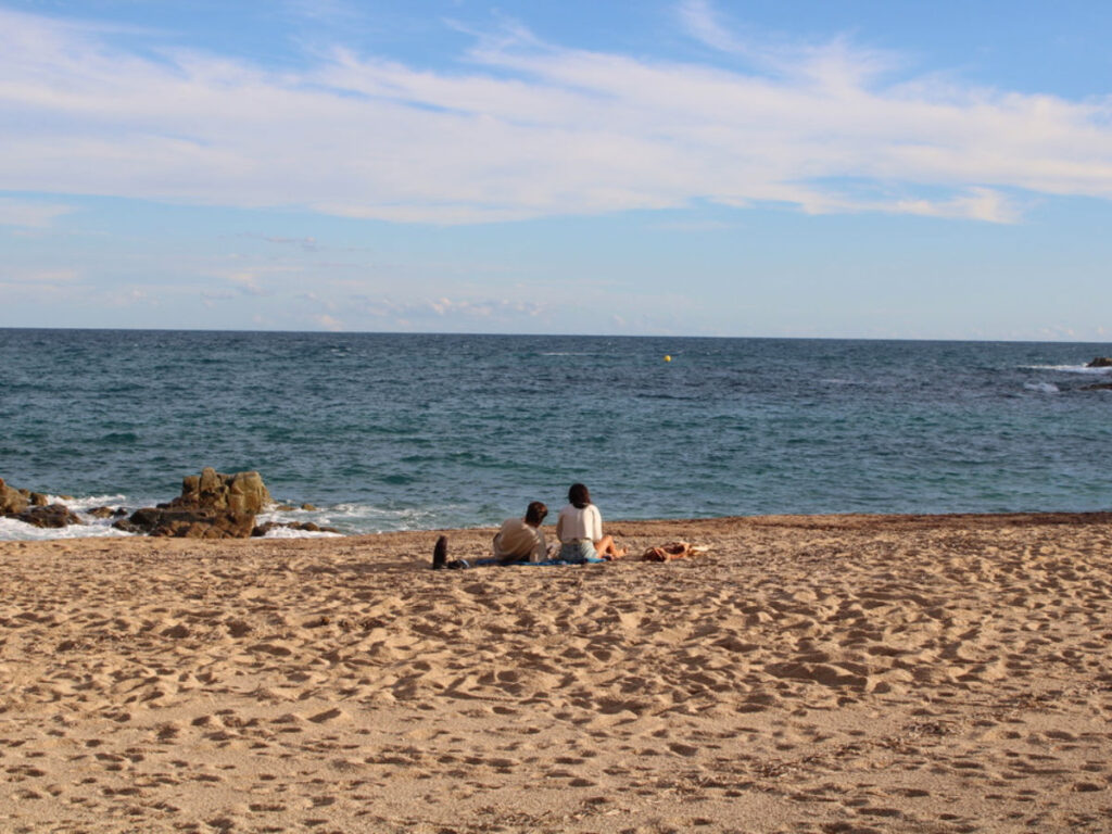 A couple sitting on the beach in Blanes