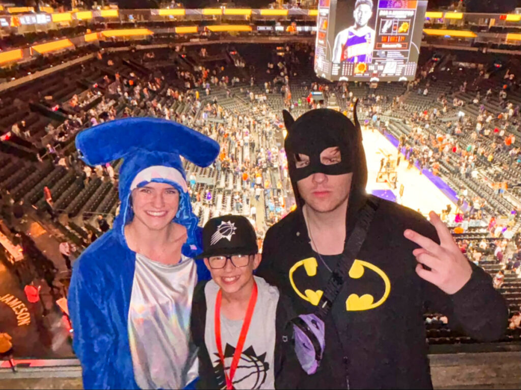 The author Betty Hurd, her boyfriend and a kid, posing for a photo at the Phoenix Suns while wearing their Halloween costumes