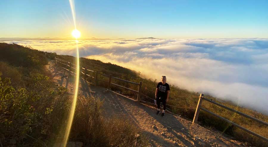 View of a woman in Cowles Mountain and the sea of clouds during sunrise