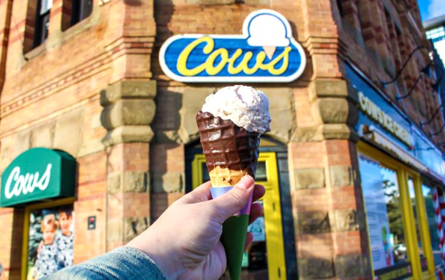 View of a hand holding an ice cream in front of the Cows Creamery entrance