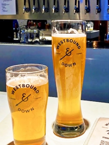 Two glasses of beer on a table and a beer tap on the background