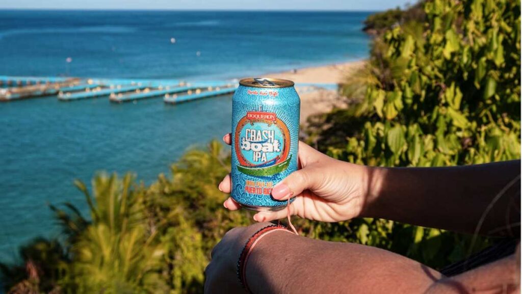 A canned beer from Crash Boat IPA with a beach view on the background