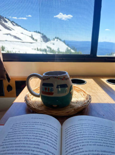A cup of coffee and a book with an overlooking view of the Crater Lake