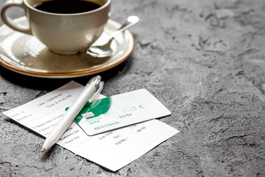 A cup of coffee, a pen, a receipt, and a credit card on a table