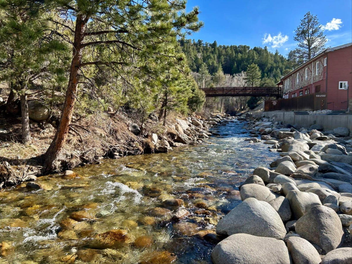 A creek winding through lined with rocks and trees at Mount Princeton Hot Springs Resort