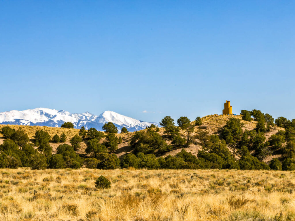View of the greenery and mountain ranges around the Crestone Ziggurat, seen from afar