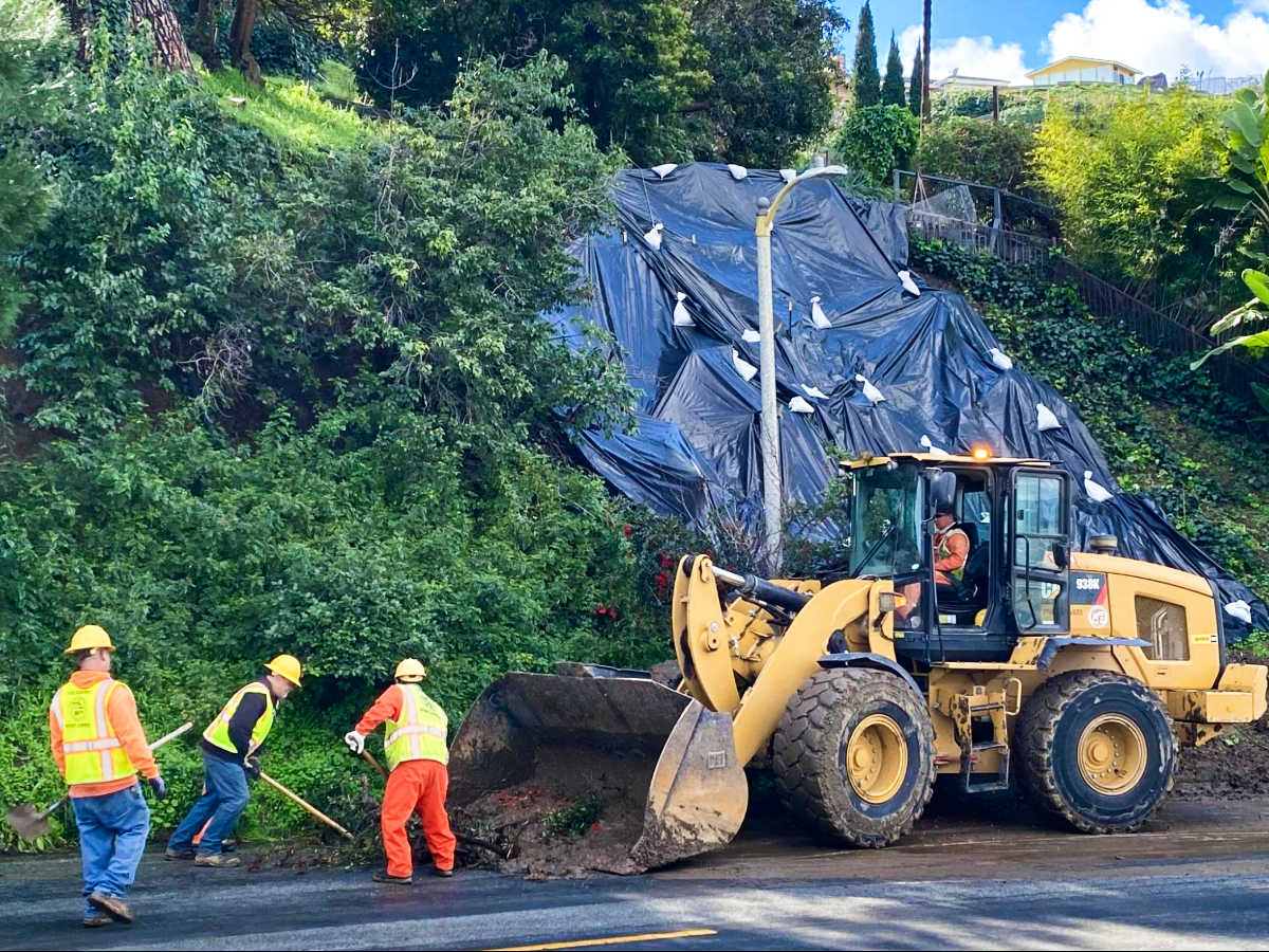 The crew cleaning up the mudslide at the side of the road in Baldwin Hills. 