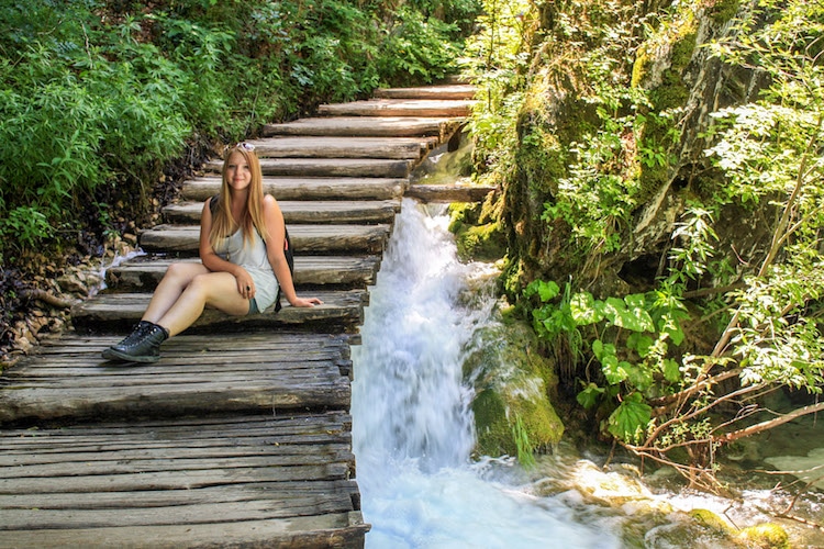 Taylor sits on steps above a waterfall in Plitvice Lakes National Park