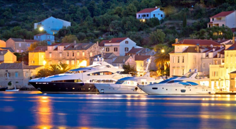 Three yachts on blue water on a dark night