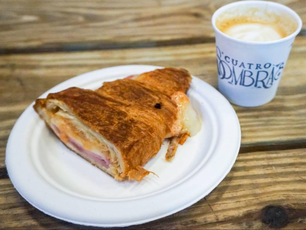 A croissant on a plate and a coffee on a cup served at Café Cuatro Sombras