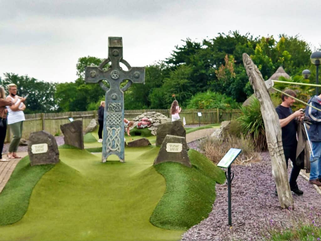 View of the people playing in the mini golf course with the Celtic cross in the middle