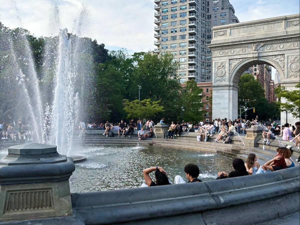 The crowd sitting around the huge fountain in Washington Square Park