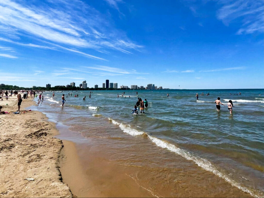 View of the people swimming at the Montrose Beach with Chicago skyline behind