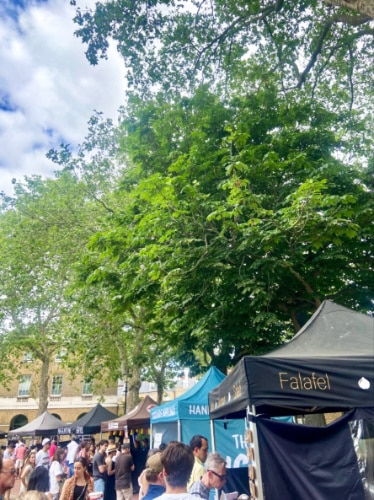 View of the crowd lining up at the row of food stands in Chelsea Fine Food Market
