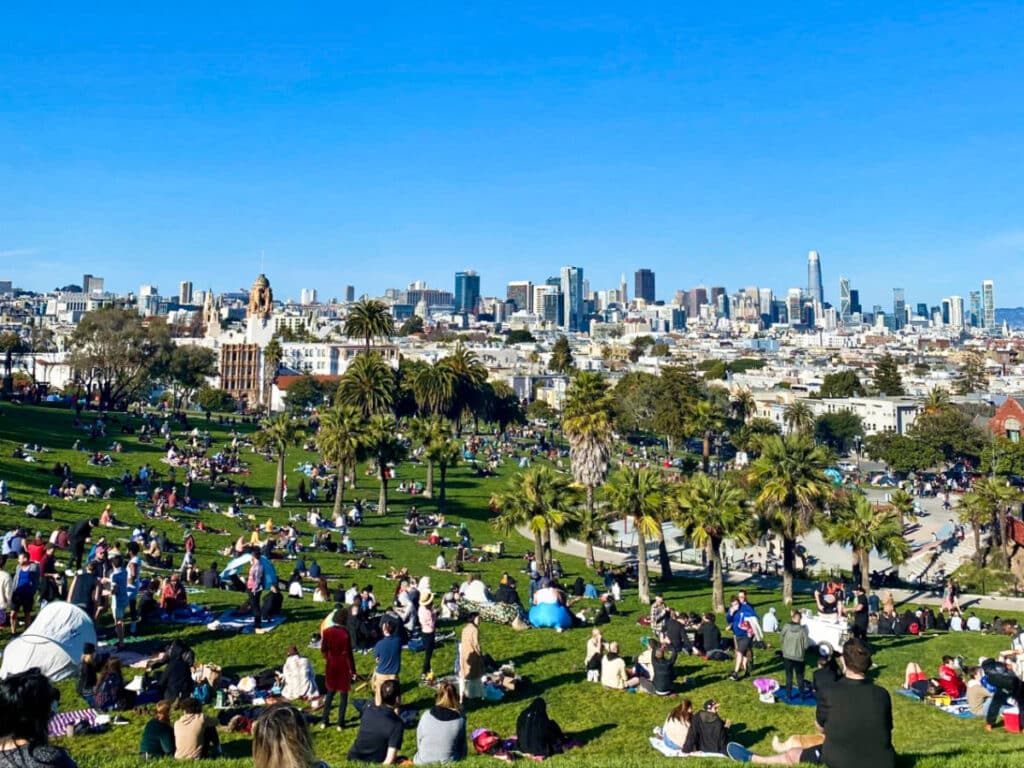 View of the crowd at the Dolores Park enjoying the San Francisco skyline on a sunny day