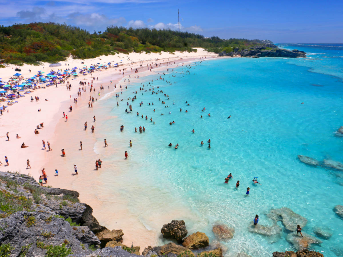 Aerial view of the crowd chilling on the Horseshoe Bay Beach with pink sand and bright blue waters