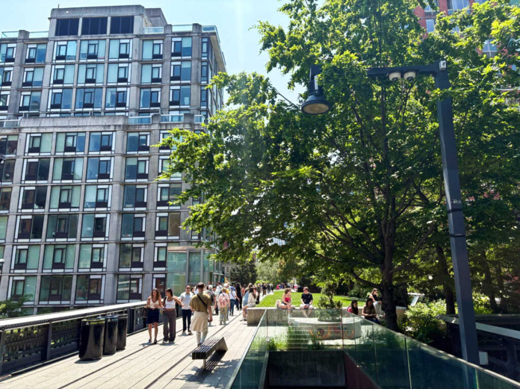 People walking along a pathway surrounded by greenery and buildings at The High Line